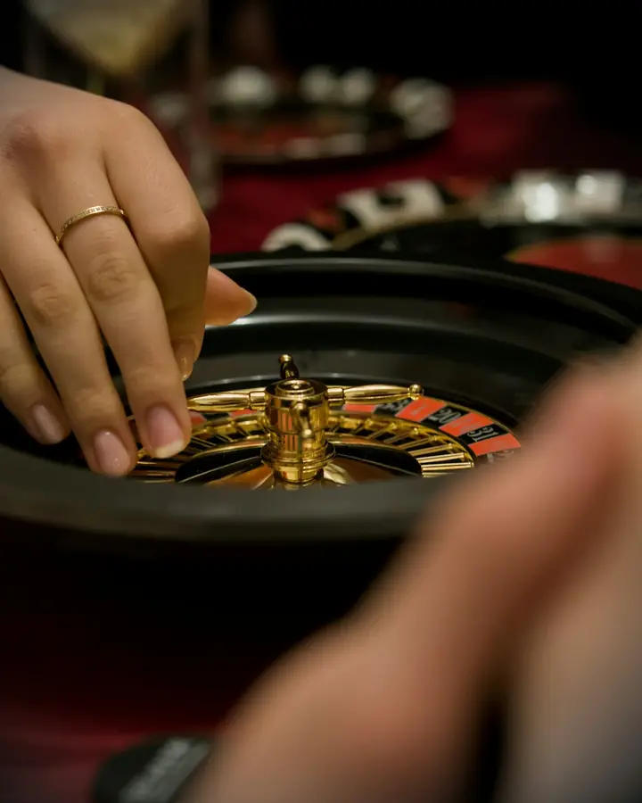 A hand placing the ball on a roulette wheel